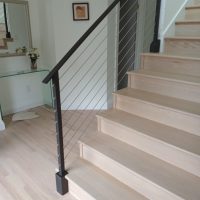 Black railing next to light beige wood stairs